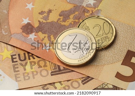 One euro and twenty cents coins on the red fifty paper bills. Royalty-Free Stock Photo #2182090917