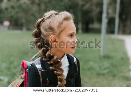 back to school. face portrait little happy kid pupil schoolgirl eight years old in fashion uniform with backpack and hairstyle voluminous long braid ready going second grade first day primary school Royalty-Free Stock Photo #2182097331