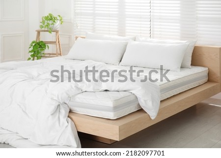 Wooden bed with soft white mattress, blanket and pillows in cozy room interior Royalty-Free Stock Photo #2182097701