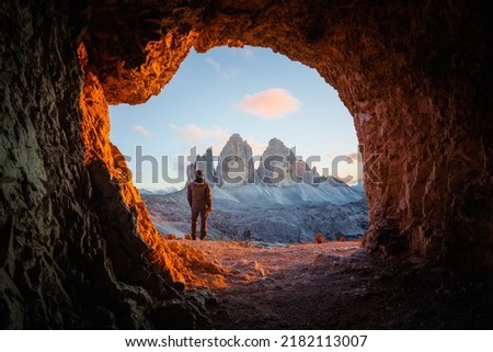 Tre Cime Di Lavaredo peaks in incredible orange sunset light. View from the cave in mountain against Three peaks of Lavaredo, Dolomite Alps, Italy, Europe. Landscape photography Royalty-Free Stock Photo #2182113007