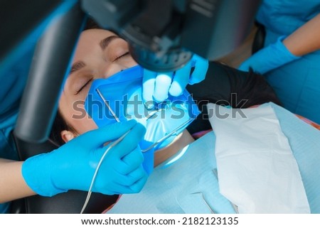 Photo endodontic treatment of dental canals in the lower molar permanent tooth molar with endodontic file with apex locator, tooth with clamp attached to it by cofferdam Royalty-Free Stock Photo #2182123135