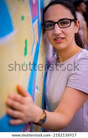 Young and beautiful woman leans against a colorful wall and poses for the camera - typical street style - travel photography