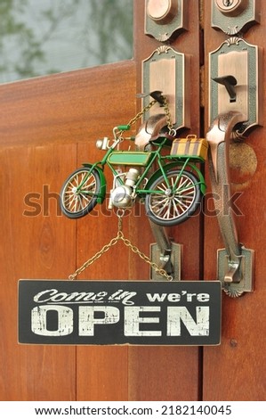 The sign reads open and a motorcycle doll hanging on the wooden door