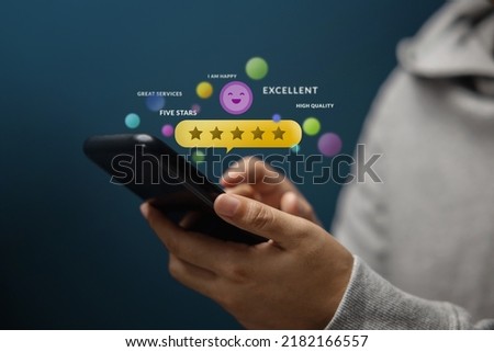 Customer Experiences Concept. Happy Client Using Smartphone to Review Five Star Rating for Online Satisfaction Surveys. Positive Feedback on Mobile Phone Royalty-Free Stock Photo #2182166557