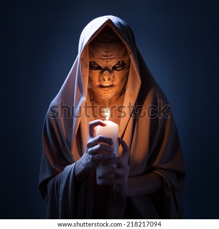 Warlock with candle in darkness. Royalty-Free Stock Photo #218217094