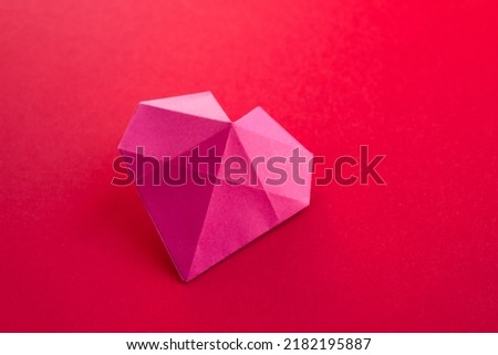 Pink paper heart origami isolated on a blank red background. Valentines day card