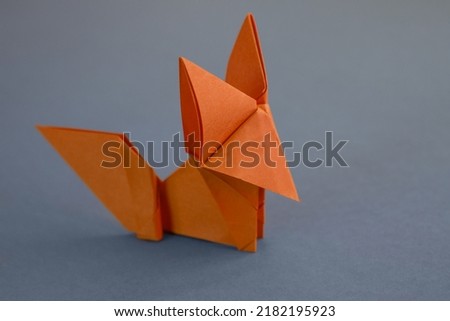 Orange paper fox origami isolated on a blank grey background.