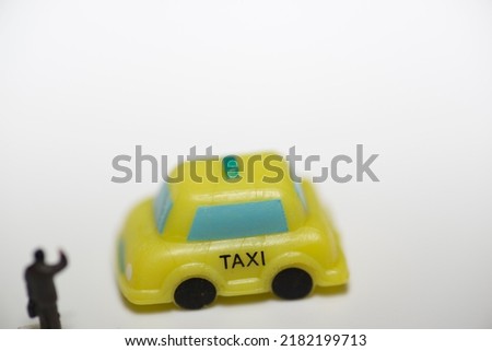 A small toy doll is calling a toy taxi.