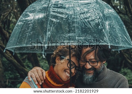 Romantic couple in love under umbrella in rainy day. Man and woman enjoy relationship and happiness together in winter autumn rain. Romance and people smiling end hugging at the park in leisure moment Royalty-Free Stock Photo #2182201929