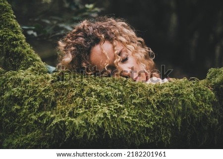 People enjoy and love feeling with green nature. Serene woman have relax and rest with face on a green soft musk trees trunk. Love outdoors park and leisure activity. Beautiful female touching nature Royalty-Free Stock Photo #2182201961