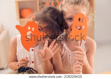 Little girls hiding faces behind paper ghosts