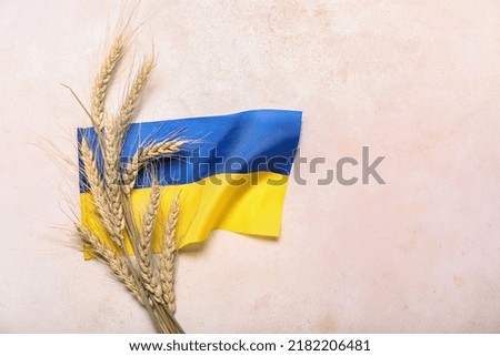 Wheat spikelets and Ukrainian flag on light background Royalty-Free Stock Photo #2182206481