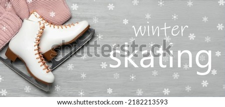 Stylish ice skates, scarf and text WINTER SKATING on wooden background