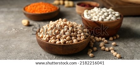 Wooden bowl with dried chickpea on grunge background