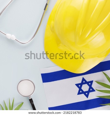 Medical care and insurance of workers in Israel. Israeli flag, stethoscope, hardhat and palm leaves on a blue background. Labor safety and right at Workplace in Israel. Flat lay