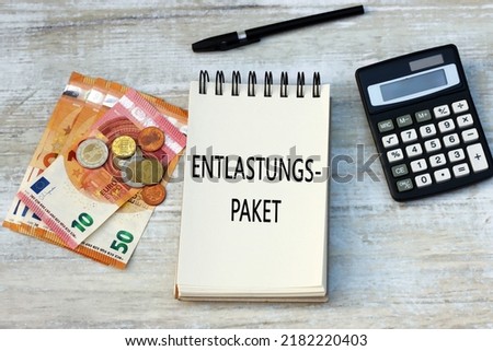 The German word Entlastungspaket  on a notepad with banknotes and a calculator.
 Entlastungspaket means relief package. Royalty-Free Stock Photo #2182220403