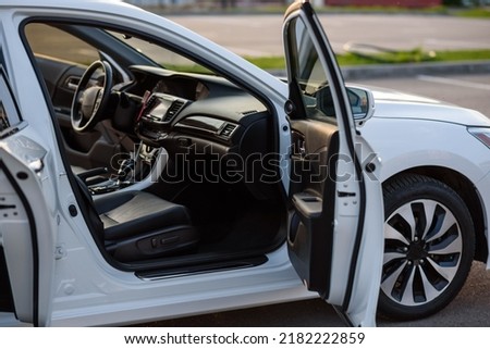 Side view of the open passenger door, mirror, dashboard of car. Right front door. A new modern shiny parked white car. Interior luxury car with tinted glass standing at parking. Modern car exterior. Royalty-Free Stock Photo #2182222859
