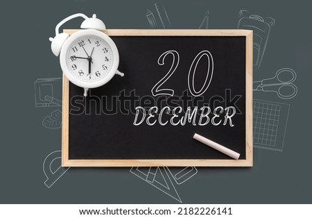 december 20. 20th day of month, calendar date. Blackboard with piece of chalk and white alarm clock on green background. Concept of day of year, time planner, winter month.