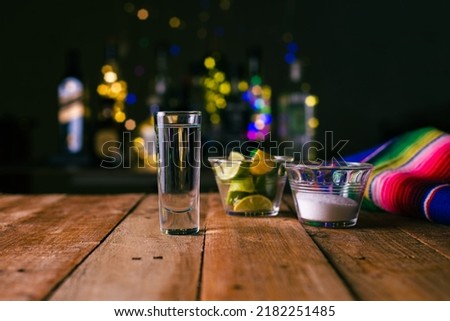 Shot of tequila served in a tequila glass on a wooden table. Blurred background. Rustic bar atmosphere. Royalty-Free Stock Photo #2182251485