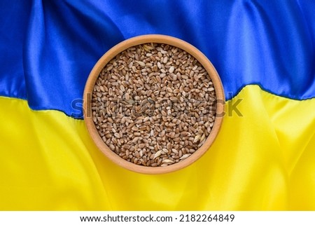 Fabric wave flag of Ukraine with wheat in wooden plate. Blue and yellow bright colors. Close up curved texture background