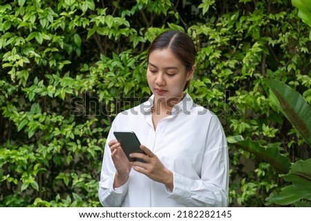 Asian women using smartphone in garden. Online business concept.