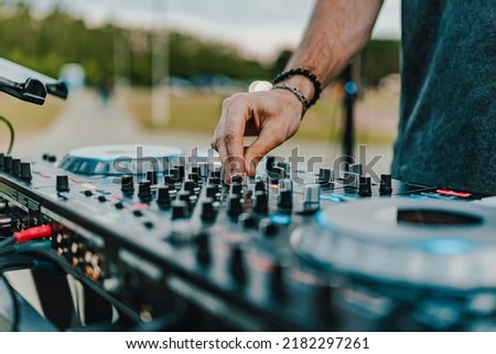 DJ Hands creating and regulating music on dj console mixer in concert outdoor Royalty-Free Stock Photo #2182297261