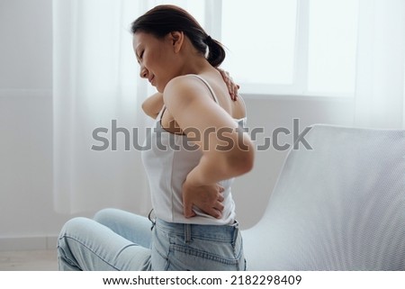 Suffering from scoliosis osteochondrosis after long study pretty young Asian woman feel hurt joint back pain laptop in incorrect posture sit on chair. Injuries Poor health Illness concept. Cool offer Royalty-Free Stock Photo #2182298409