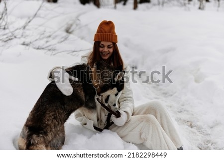 Happy young woman winter clothes walking the dog in the snow winter holidays