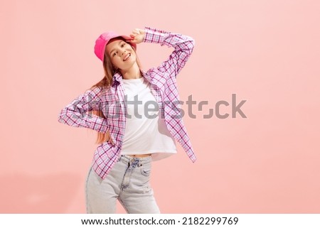 Portrait of young girl posing in stylish summer outfit with panama isolated over pink studio background. Concept of beauty, style, lifestyle, youth, emotions, facial expression. Copy space for ad