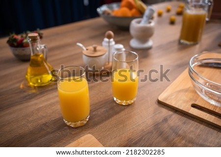 Cutting board with fresh oranges and juice in glass on table in kitchen