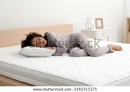 Young African American woman sleeping on bed with comfortable mattress and pillow at home Royalty-Free Stock Photo #2182311371