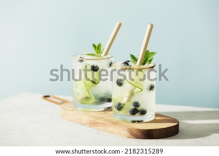 Trendy summer drinks with cucumber, mint and blueberry on blue sky background Royalty-Free Stock Photo #2182315289