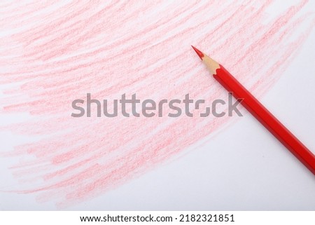 Red pencil on sheet of paper with drawing, top view
