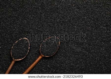Wooden spoons on pile of black sesame seeds, flat lay. Space for text
