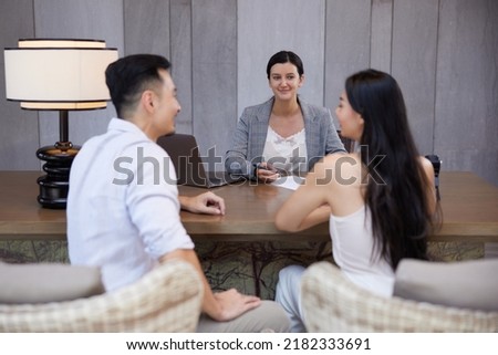 Young happy asian couple talking to banker or consulting agent, making legal deal, taking loan or mortgage, purchasing real estate, new apartment or house