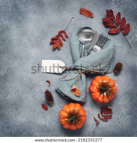 Thanksgiving autumn place setting with cutlery, decorative pumpkins and colorful leaves. Top view, flat lay., copy space. Square Toned Photo. Textured object, selective focus.