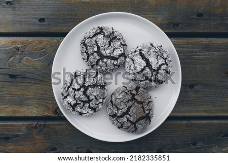 Homemade almond cookies with cocoa sprinkled with powdered sugar on a plate on a wooden background