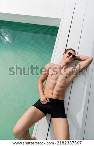 top view of happy man in swimming trunks and sunglasses relaxing near pool Royalty-Free Stock Photo #2182337367