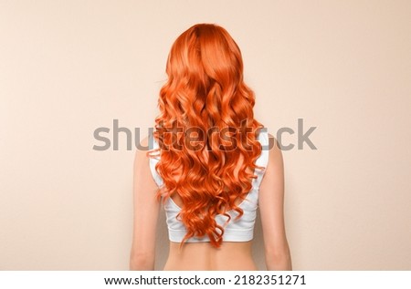 Beautiful woman with long orange hair on beige background, back view Royalty-Free Stock Photo #2182351271