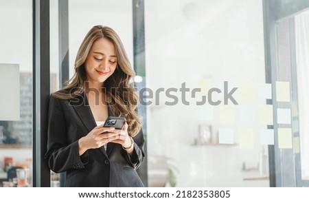 Charming brunette Asian business woman using mobile phone, Pretty Asian lady massaging in cellphone at modern office.