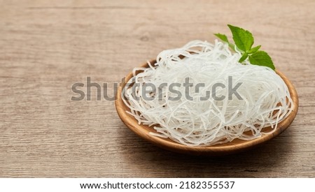 Asian vermicelli or cellophane noodles in wooden plate on wood table background. glass noodle                                                                               Royalty-Free Stock Photo #2182355537