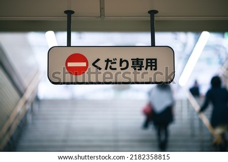 Sign reading "kudari senmon" (down only) on steps in a Japanese subway system with the international do not enter emblem.  Royalty-Free Stock Photo #2182358815
