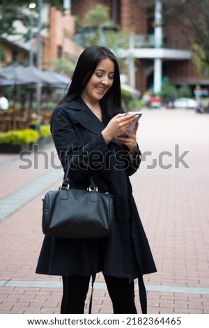 Happy woman watching a video on mobile phone on city street.