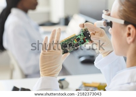 Close up of female engineer inspecting electronic parts in laboratory, copy space Royalty-Free Stock Photo #2182373043