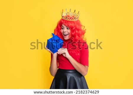 amazed child in tiara with present box on yellow background