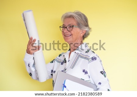 Smiling attractive senior woman holding laptop under her arm while talking. Elderly romantic beautiful teacher or architect going to class