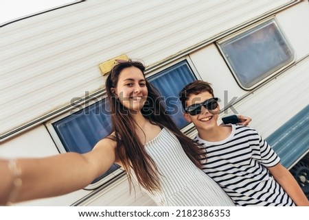 Brother and sister standing in front of a camper on a seaside holiday