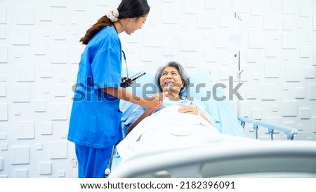 Female doctor enters patient room to inquire about the symptoms of an elderly woman who was receiving saline in a bed in the patient room. Female doctor talking to female patient about better.