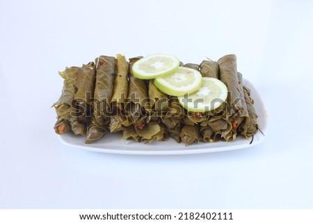 Turkish cuisine food Yaprak Sarma (Wrap stuffed) with lemon slices. Grape leaves stuffed with bulgur isolated on white. Sitting view, close up of traditional Turkish or Greek cuisine culture food. Royalty-Free Stock Photo #2182402111