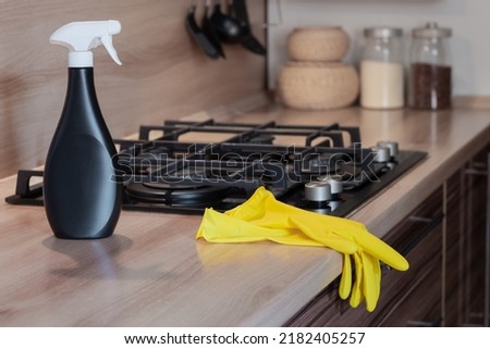 professional cleaning, yellow rubber gloves and a bottle of cleaning agent in a clean kitchen